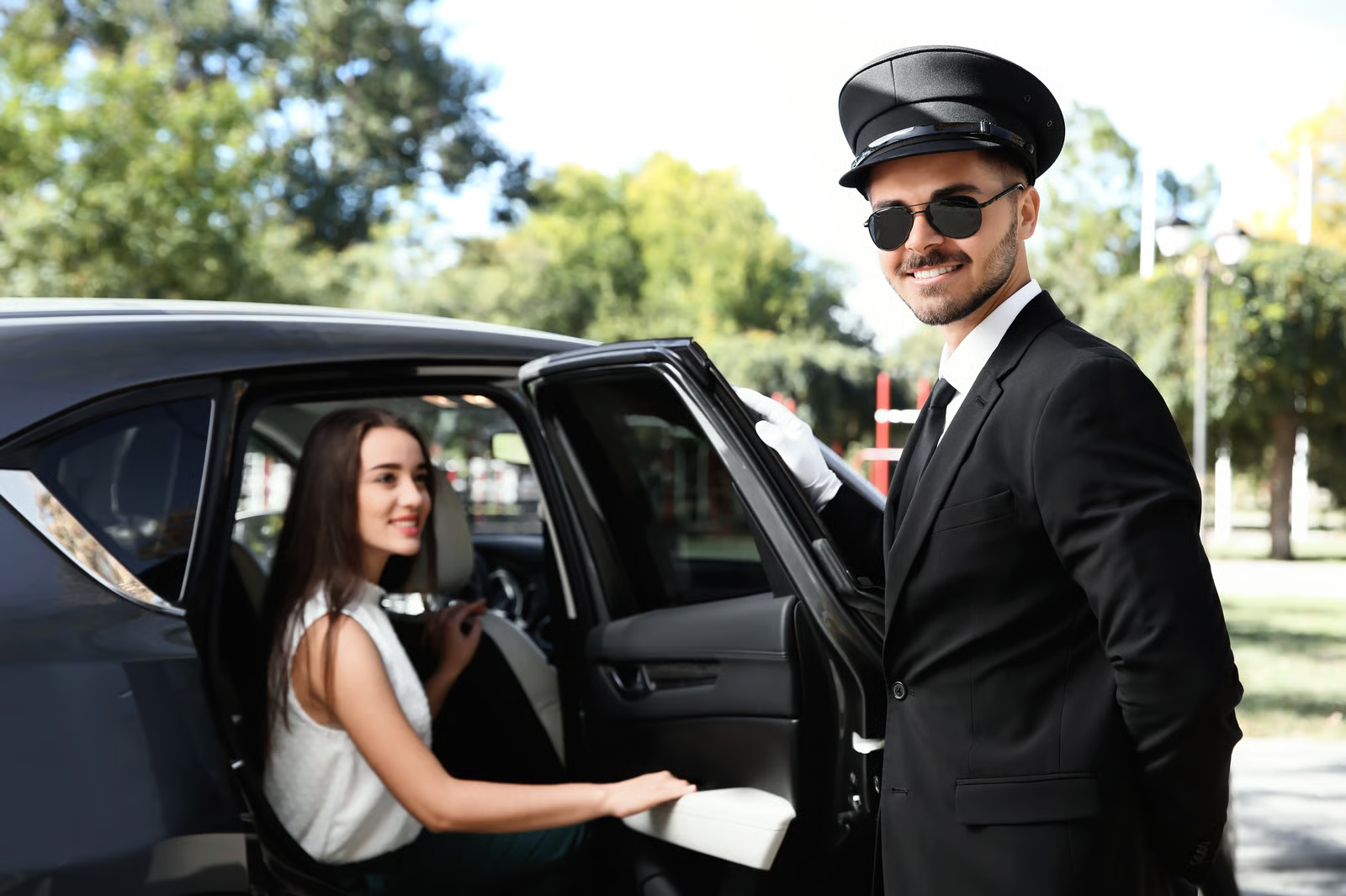 Chauffeur mit Mütze und Handschuhen öffnet die Tür für einen Passagier